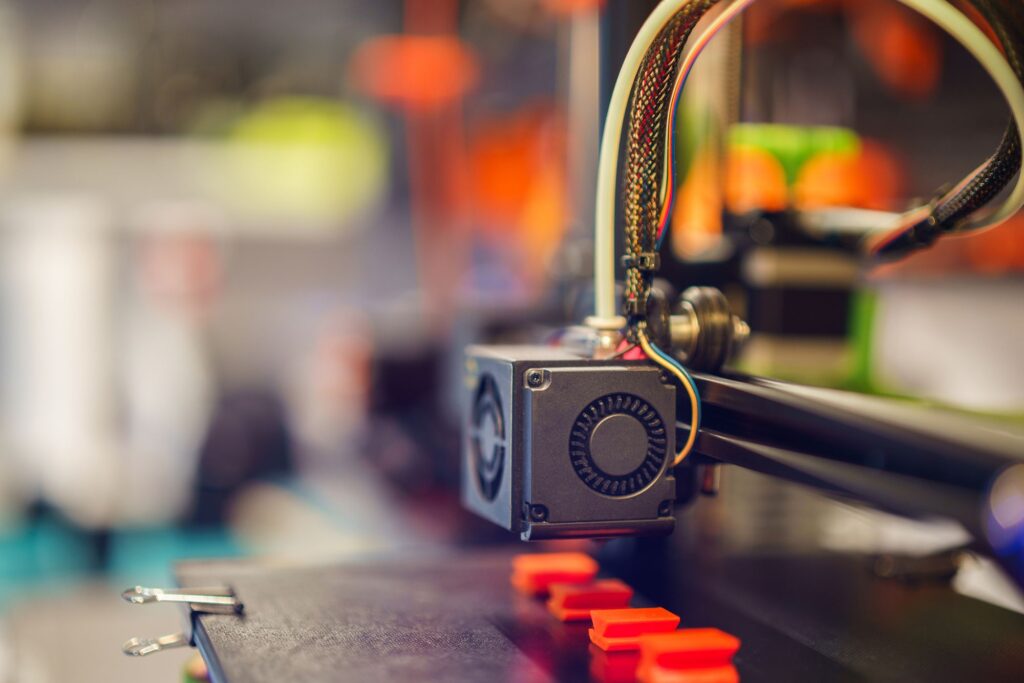 Cabezal de impresora 3D FDM fabricando piezas de utillaje en plástico naranja