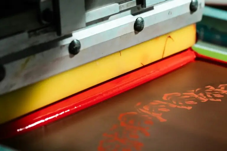 Rasqueta de una máquina de serigrafía plana depositando tinta roja sobre la pantalla