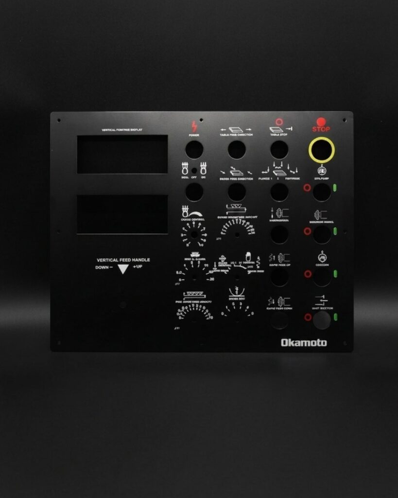 Panel de control metálico negro con indicaciones y simbología serigrafiadas a varias tintas
