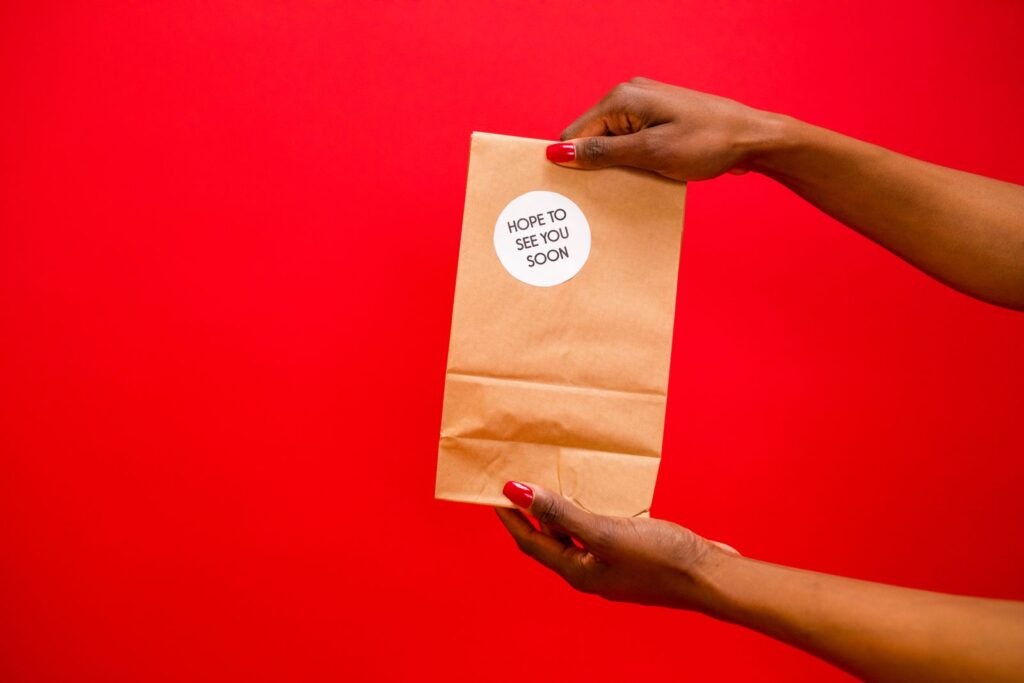 Bolsa de papel kraft cerrada con pegatina redonda sobre fondo rojo
